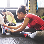 Three young adults stretching indoors at a gym