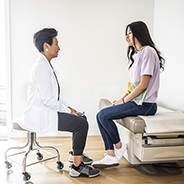 Doctor talking privately with teen in exam room