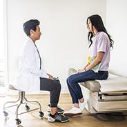 Doctor talking privately with teen in exam room