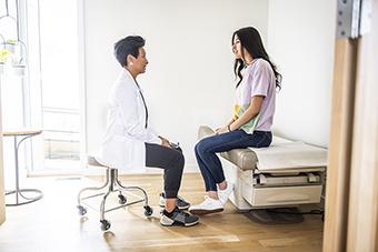 Doctor talking privately with teen in exam room
