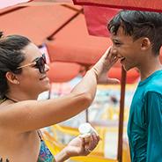 mom putting sunscreen on son